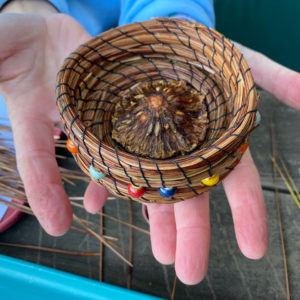 hand holding a handwoven Pine needle basket