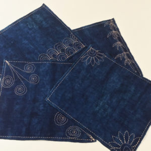 close up of linen place mats with sashiko and kantha embroidery stitching with white background