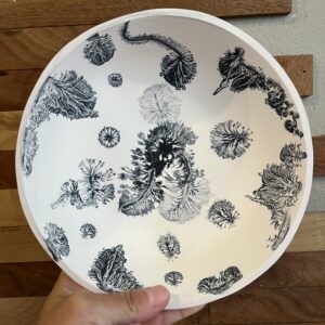 hand holding a piece of clay pottery with tie dye surface design