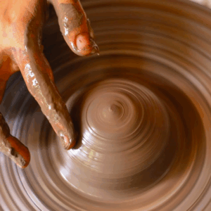 hands working on a ceramic piece on a pottery wheel